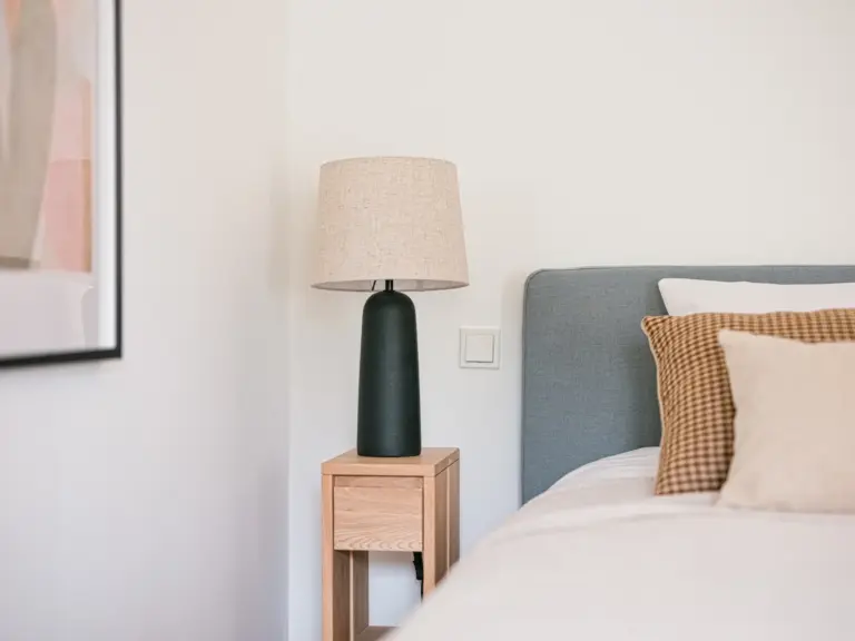 Bedside lamp on wooden nightstand in OPAL GREEN bedroom