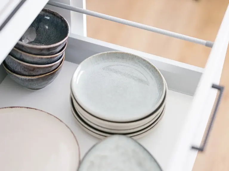 Stacked plates and bowls in kitchen cabinet of OPAL BLUE TDY and TLA apartment