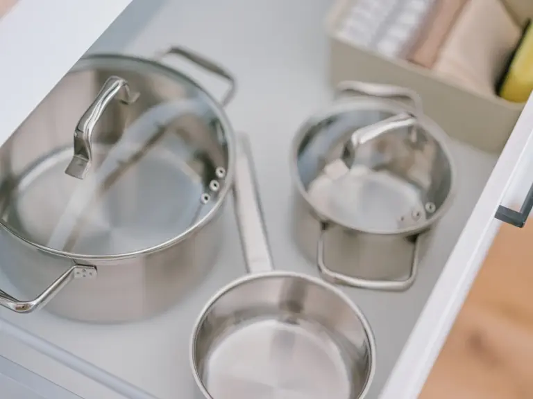 Stainless steel pots and pans stored in kitchen drawer of OPAL BLUE TLA apartment