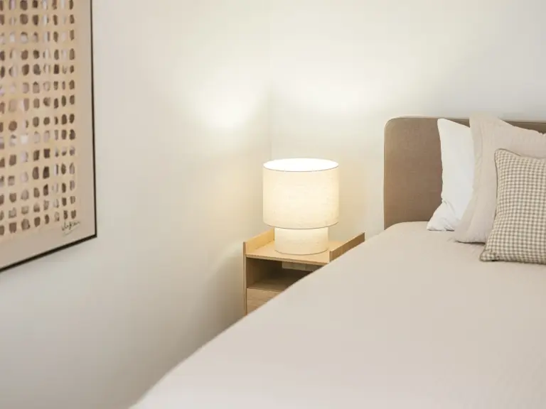 Side perspective of the master bedroom at OPAL BLUE, showing the king-size bed, wooden bench, radiator and natural daylight. Fully furnished TLA housing near Ramstein Air Base suitable for TDY and PCS stays.