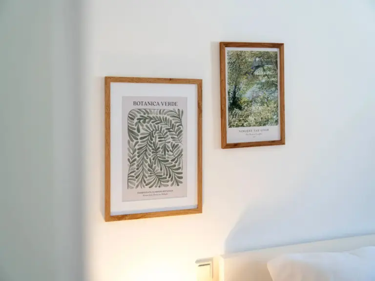 Framed botanical and landscape wall art above bed in modern bedroom of Opal White