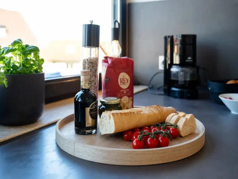 Fresh baguette with cherry tomatoes and olive oil on a kitchen counter