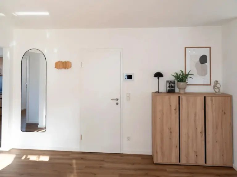 Minimalist apartment hallway with wooden cabinet, mirror, and modern wall decor