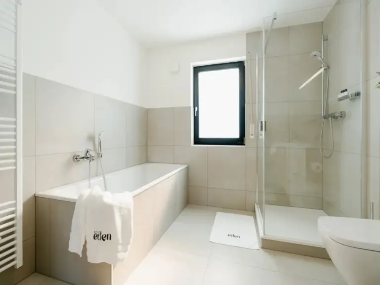 Modern bathroom with bathtub and glass shower in Opal White apartment
