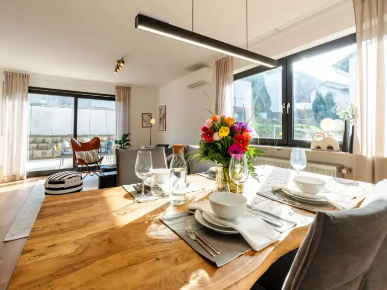 Set dining table with flowers and view into living area in Opal White apartment