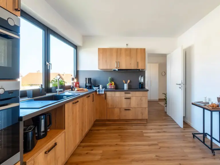 Spacious kitchen with wood cabinetry and large windows in Opal White apartment