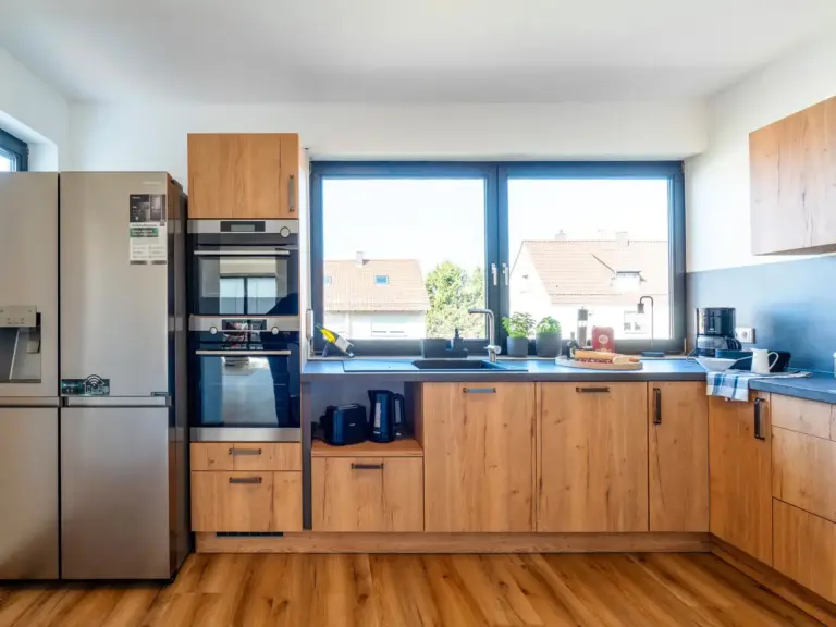 Modern kitchen with large windows and side-by-side fridge in Opal White apartment