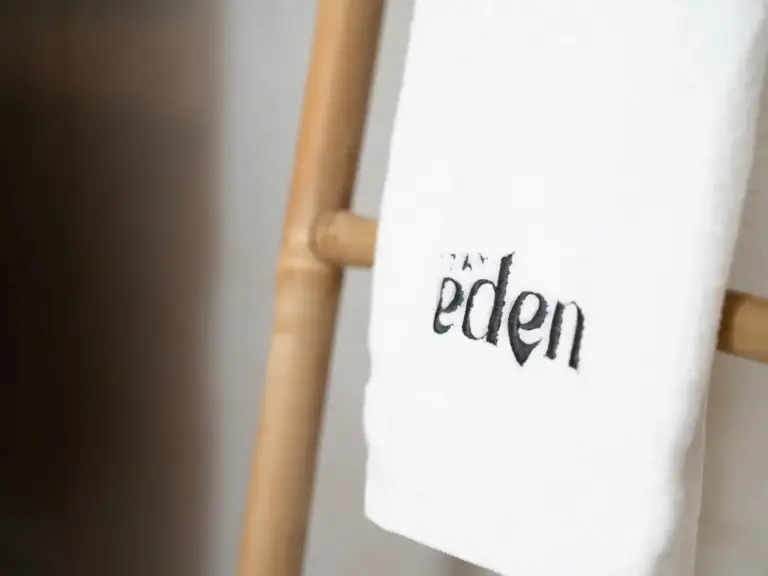 Stay Eden branded towel detail on wooden ladder in modern apartment Opal White