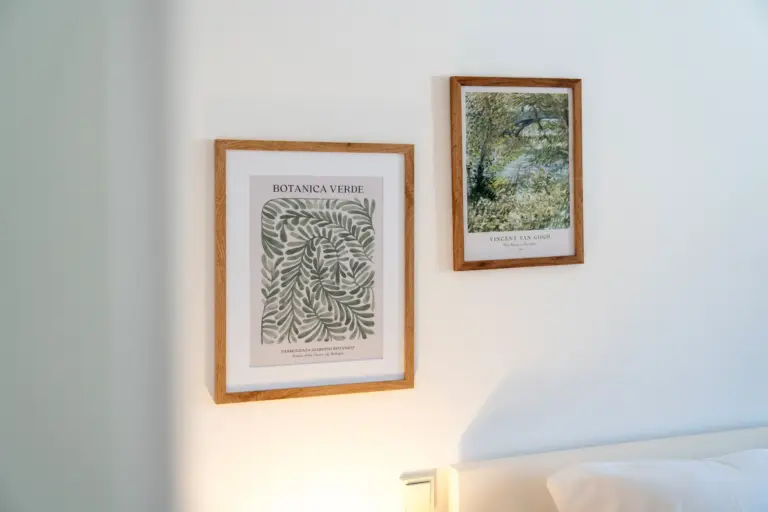 Framed botanical and landscape wall art above bed in modern bedroom of Opal White