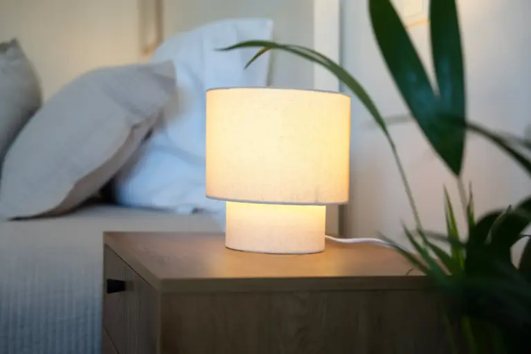 Warm bedside lamp on wooden nightstand in modern bedroom