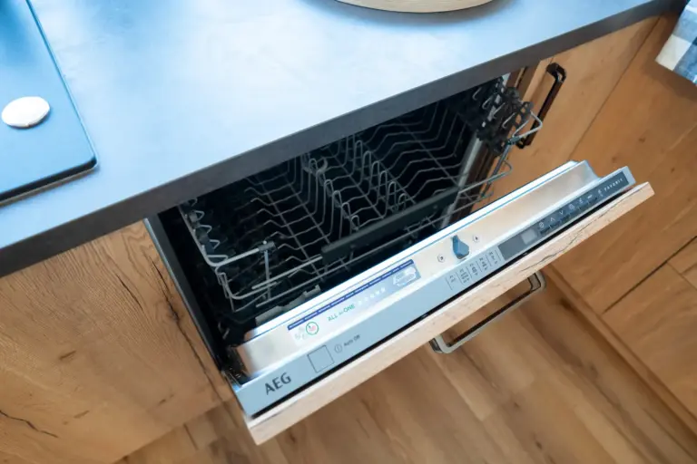 Built-in dishwasher open in modern kitchen with wooden cabinets