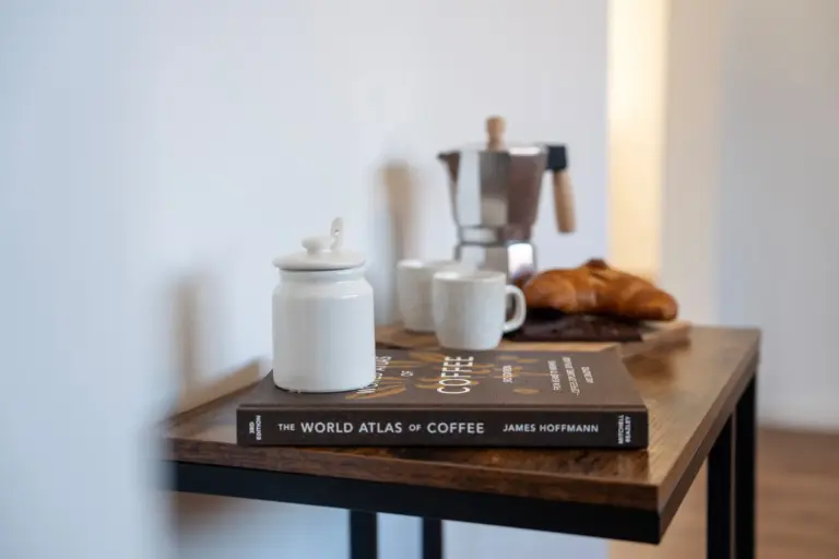 Coffee setup with cups, moka pot, and croissant o a wooden table