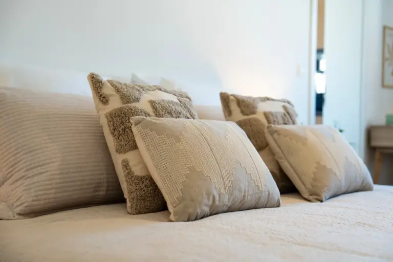 Decorative pillows arranged on a neatly made bed in a bright bedroom