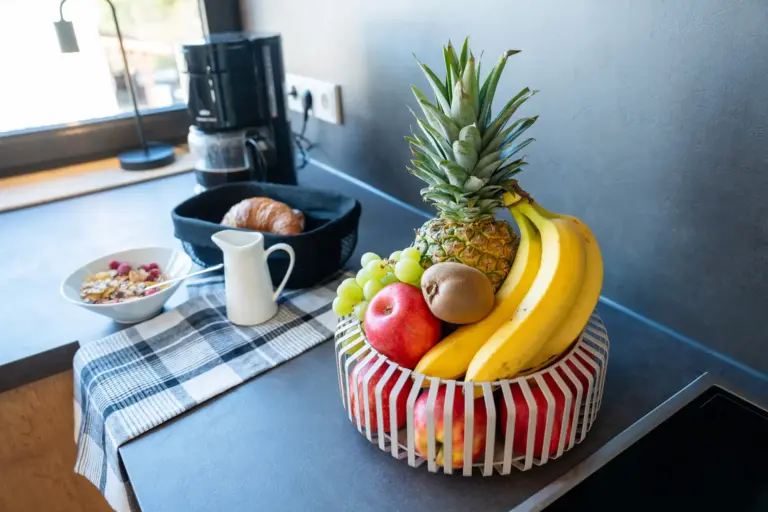 Fruit basket with pineapple, bananas, and apples on modern kitchen counter