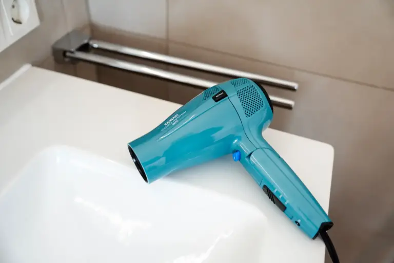 Hair dryer placed on bathroom sink in modern furnished apartment Opal White