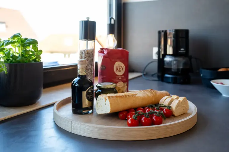Fresh baguette with cherry tomatoes and olive oil on a kitchen counter