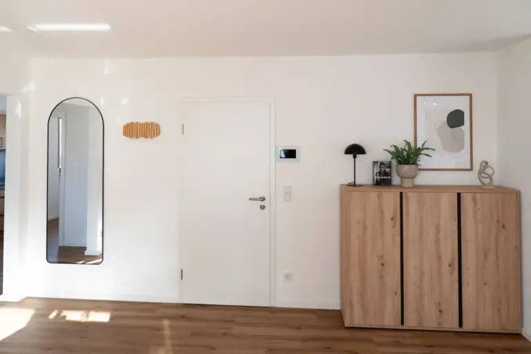 Minimalist apartment hallway with wooden cabinet, mirror, and modern wall decor
