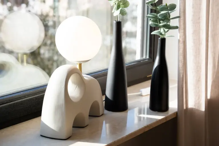 Modern decorative lamp and vases with plants on a window sill