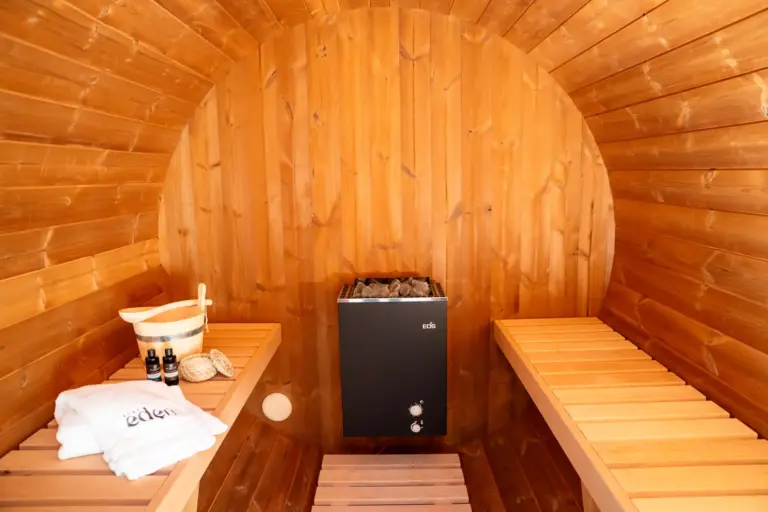 Spacious wooden sauna interior with benches and EOS heater in Opal apartment house