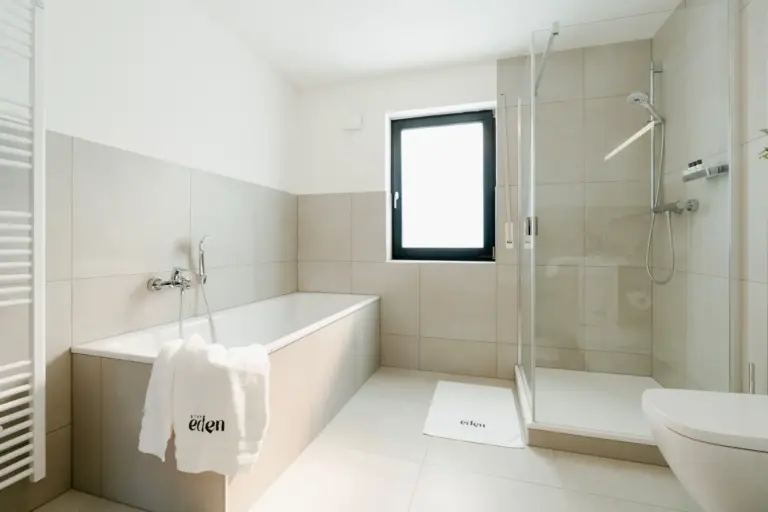 Modern bathroom with bathtub and glass shower in Opal White apartment
