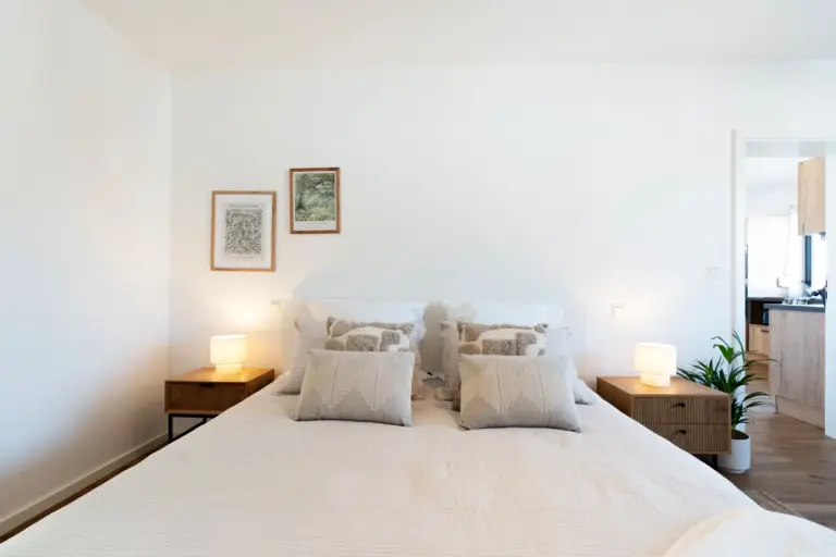 King-size bed with pillows and bedside lamps in Opal White apartment bedroom