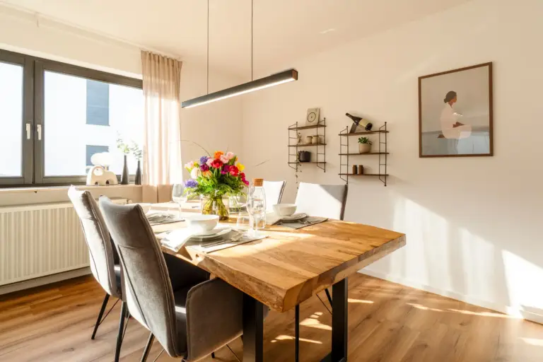 Dining area with wooden table and set table in Opal White apartment
