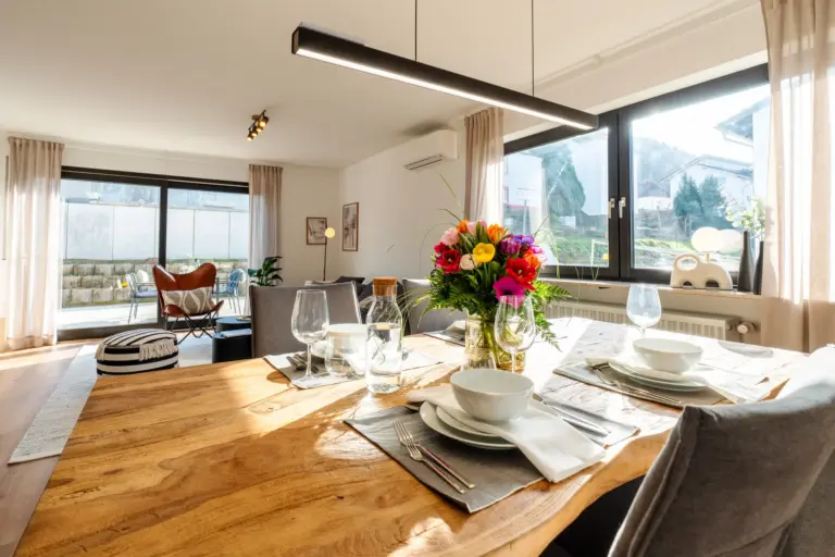 Set dining table with flowers and view into living area in Opal White apartment