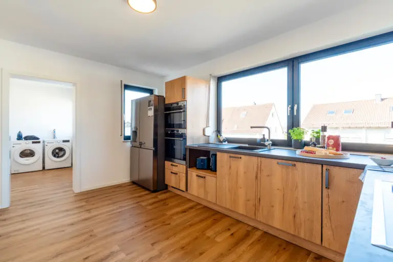 Kitchen with window view and access to laundry room in Opal White apartment