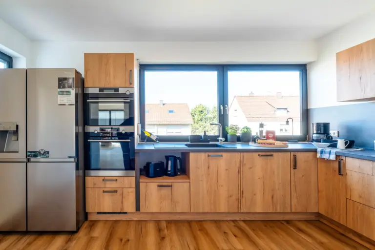Modern kitchen with large windows and side-by-side fridge in Opal White apartment