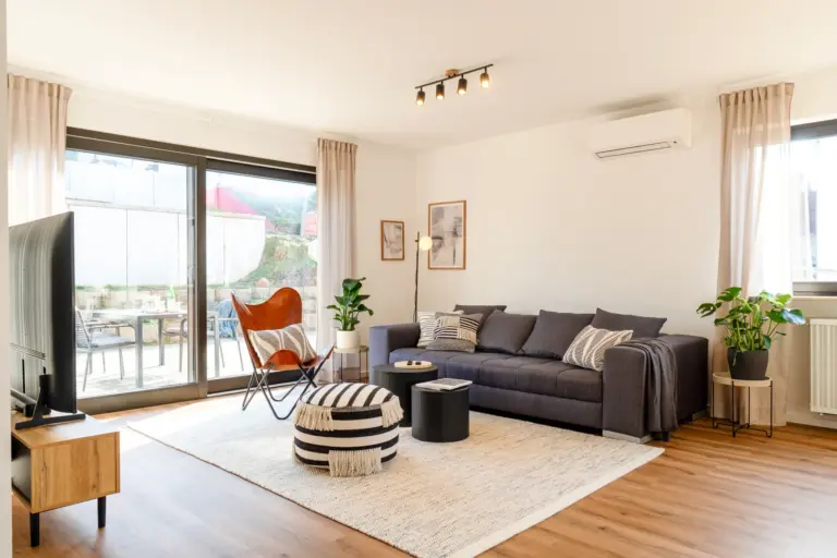 Bright living room with sofa, lounge chair and terrace access in Opal White apartment