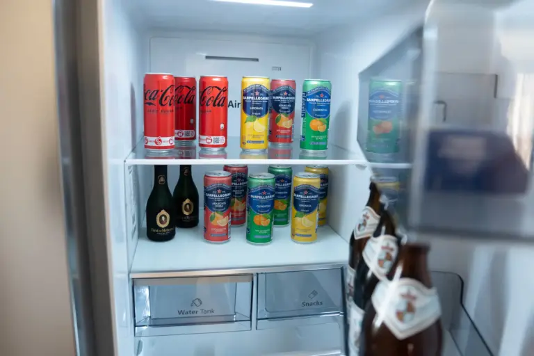 Fully stocked side-by-side fridge with soft drinks, sparkling beverages and bottled drinks