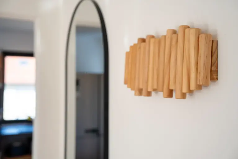 Close-up of a wooden wardrobe next to a mirror in a modern apartment hallway