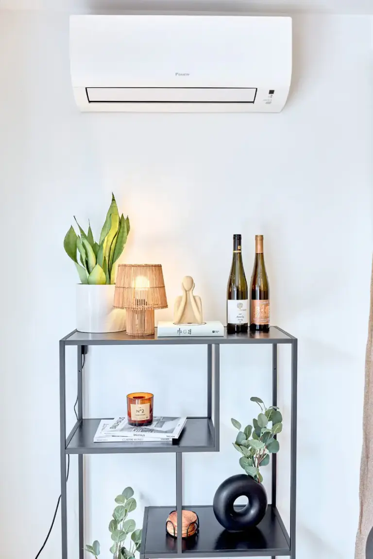 Air conditioning unit above a stylish decorative shelf with plants and warm lighting in CORAL BLOOM