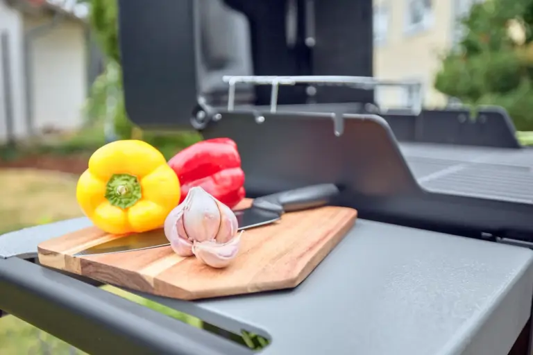 Fresh peppers and garlic on a wooden cutting board beside the CORAL BLOOM barbecue