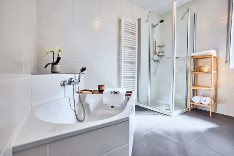 Bright CORAL BLOOM bathroom with bathtub, separate glass shower, heated towel rack and fresh towels