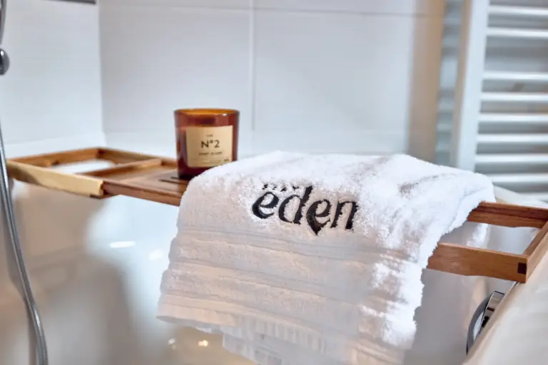 Stay Eden towel and candle arranged on the bathtub in CORAL BLOOM's bathroom