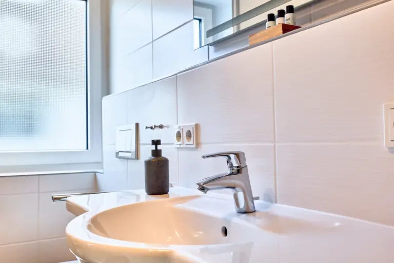 Bathroom vanity in CORAL BLOOM with white basin, chrome faucet, mirror and toiletries