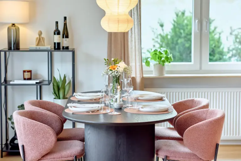 Dining area at CORAL BLOOM with dark dining table, four coral-colored chairs, elegant table setting and floral centerpiece