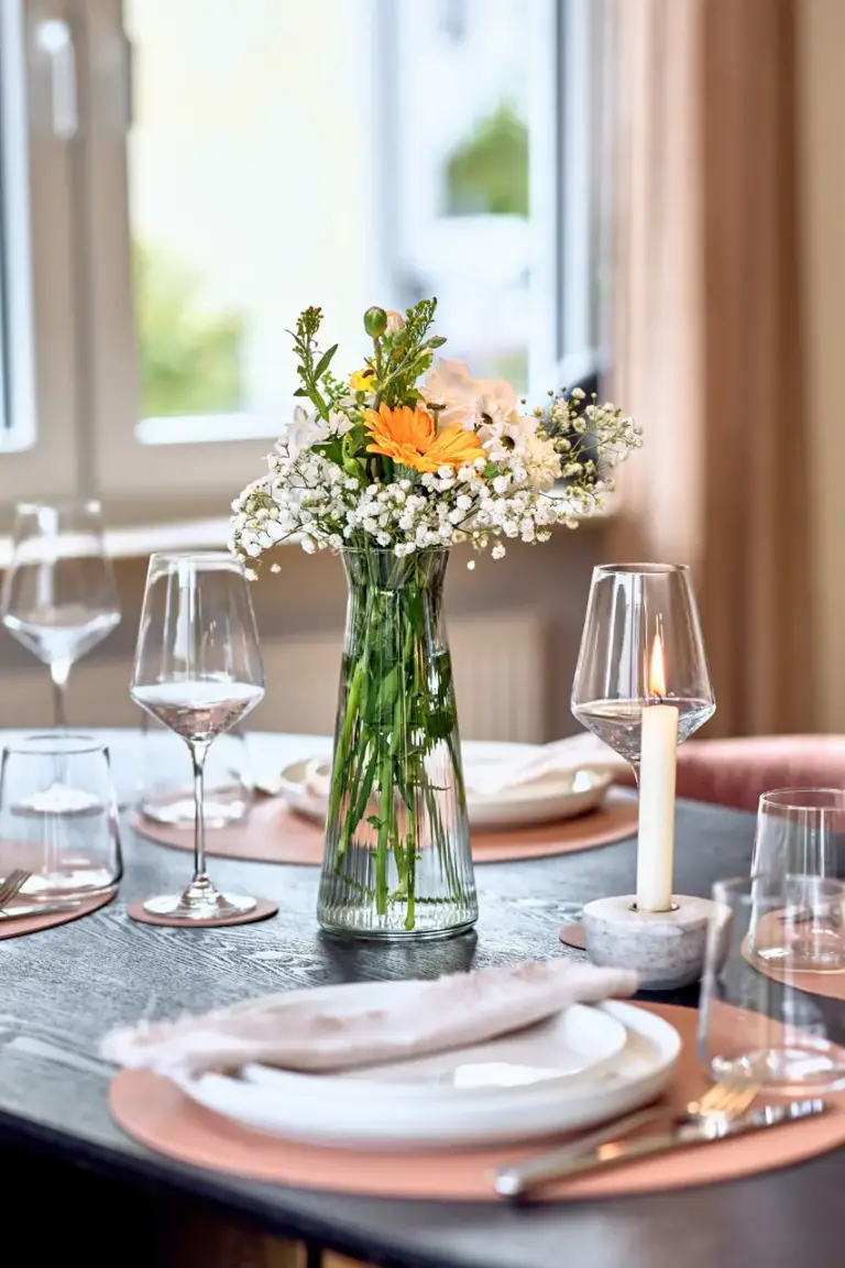 Fresh floral centerpiece with candle and elegant table setting in the dining area at CORAL BLOOM