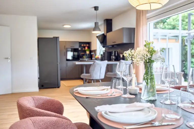 CORAL BLOOM dining table with elegant place settings and flowers overlooking the modern kitchen
