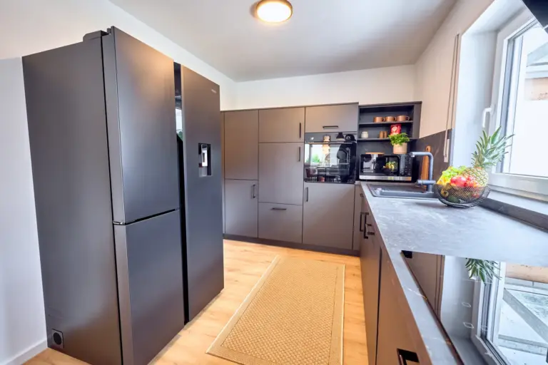 CORAL BLOOM modern kitchen with dark cabinetry, side-by-side refrigerator and built-in appliances