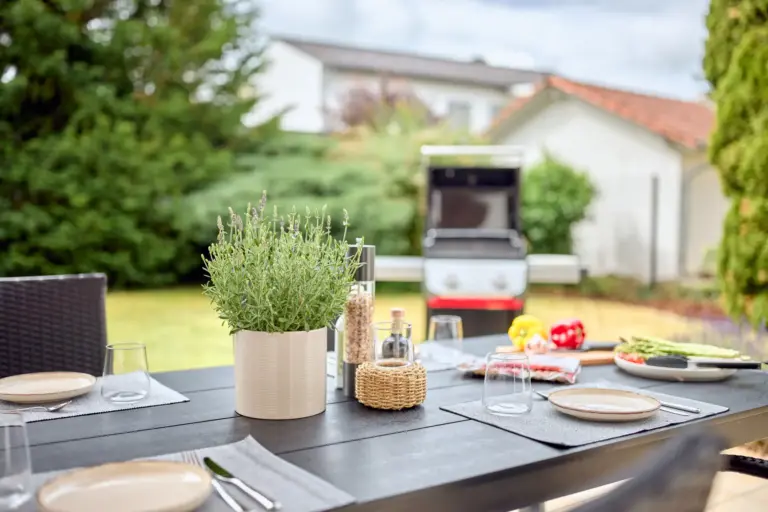Outdoor dining table with barbecue and lush garden views at CORAL BLOOM