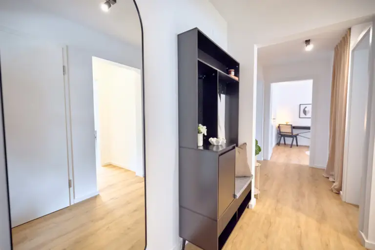 CORAL BLOOM hallway with black entryway storage, full-length mirror and warm wood flooring