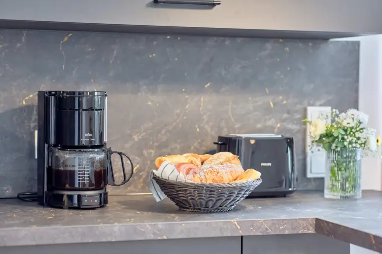 Kitchen counter at CORAL BLOOM with coffee maker, toaster, fresh pastries and flowers