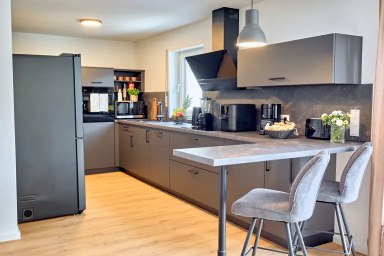 Modern kitchen at CORAL BLOOM with dark cabinetry, spacious countertops, breakfast bar, bar stools and contemporary appliances