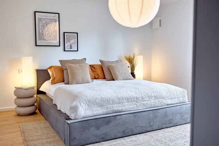 Spacious master bedroom with a large upholstered bed and warm neutral décor at CORAL BLOOM