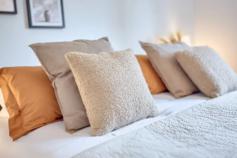 Soft textured pillows in warm neutral and earthy tones on the master bed at CORAL BLOOM