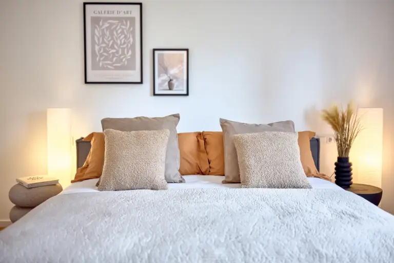 Elegant master bedroom with a large bed, warm lighting and neutral décor at CORAL BLOOM