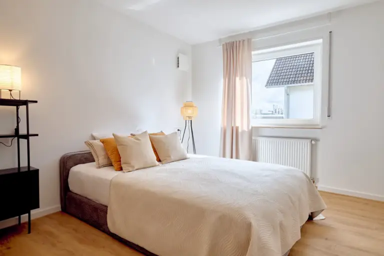 Bright second bedroom in CORAL BLOOM with a double bed, neutral textiles and warm lighting