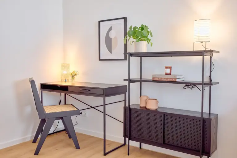 Dedicated work corner in the second bedroom at CORAL BLOOM with dark desk, woven chair, shelving and warm lighting